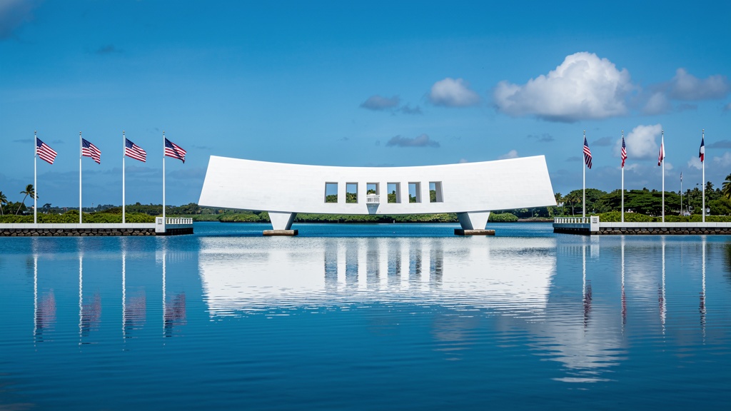 USS Arizona Memorial at Pearl Harbor reflected in calm harbor waters with American flag